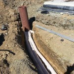 white warer pipe being installed in a trentch